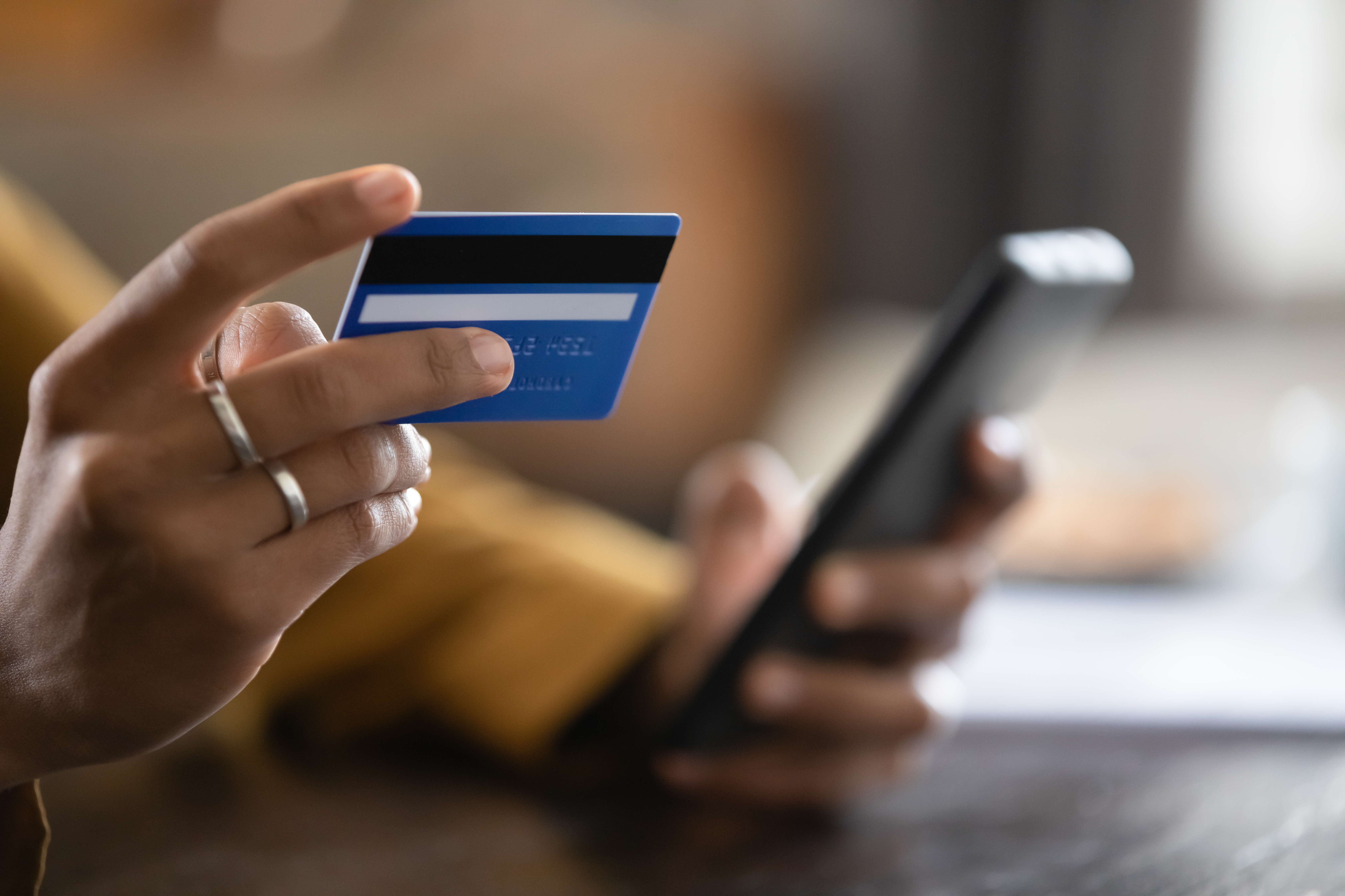 Foto close up seorang wanita yang sedang berbelanja menggunakan kartu kredit dan smartphone